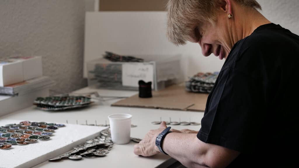 Mitarbeitende der Talentwerkstatt bei der Herstellung der Scheiben aus Kaffeekapseln.