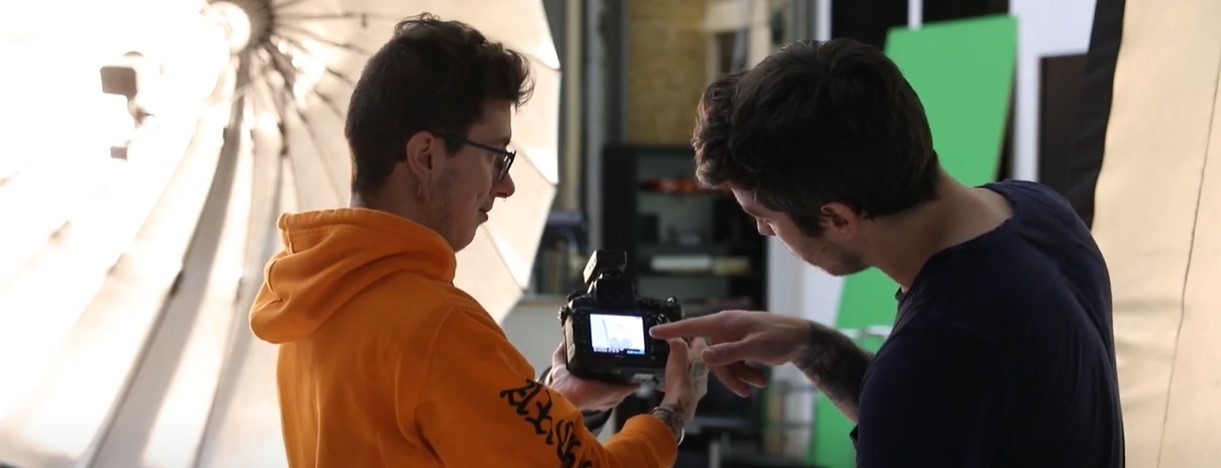 Lernender Fotomedienfachmann mit Ausbildner im Fotostudio beim Einrichten der Kamera