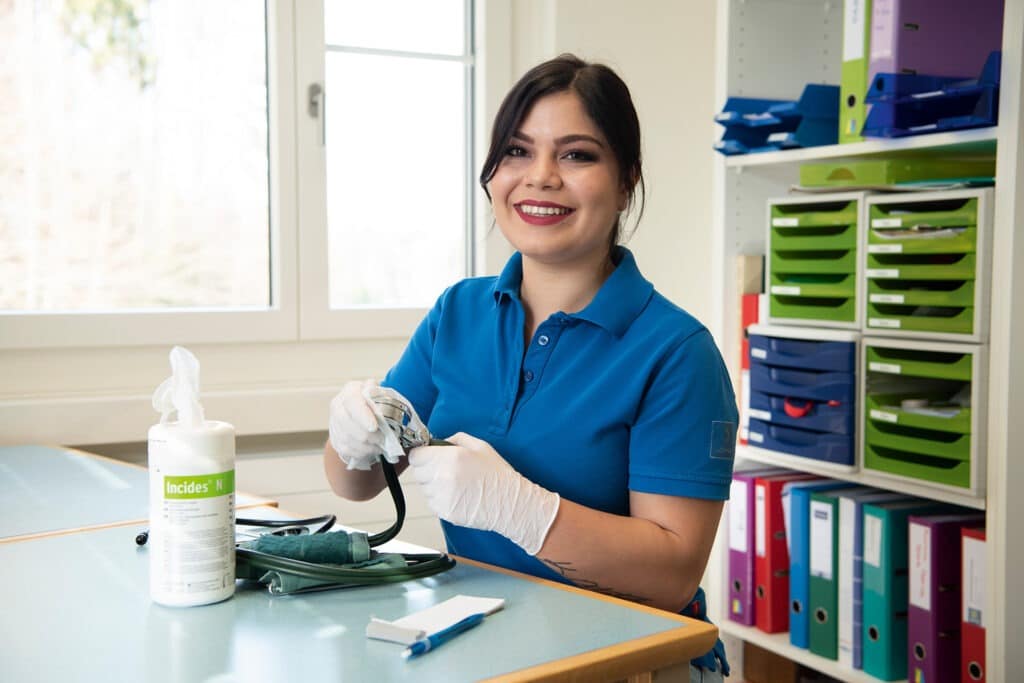 Lächelde Pflegerin reinigt ein Blutdruckmessgerät
