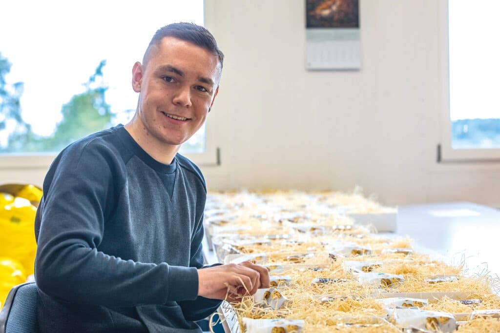 Junger Mann konfektioniert  eine Reihe von Geschenkschachteln