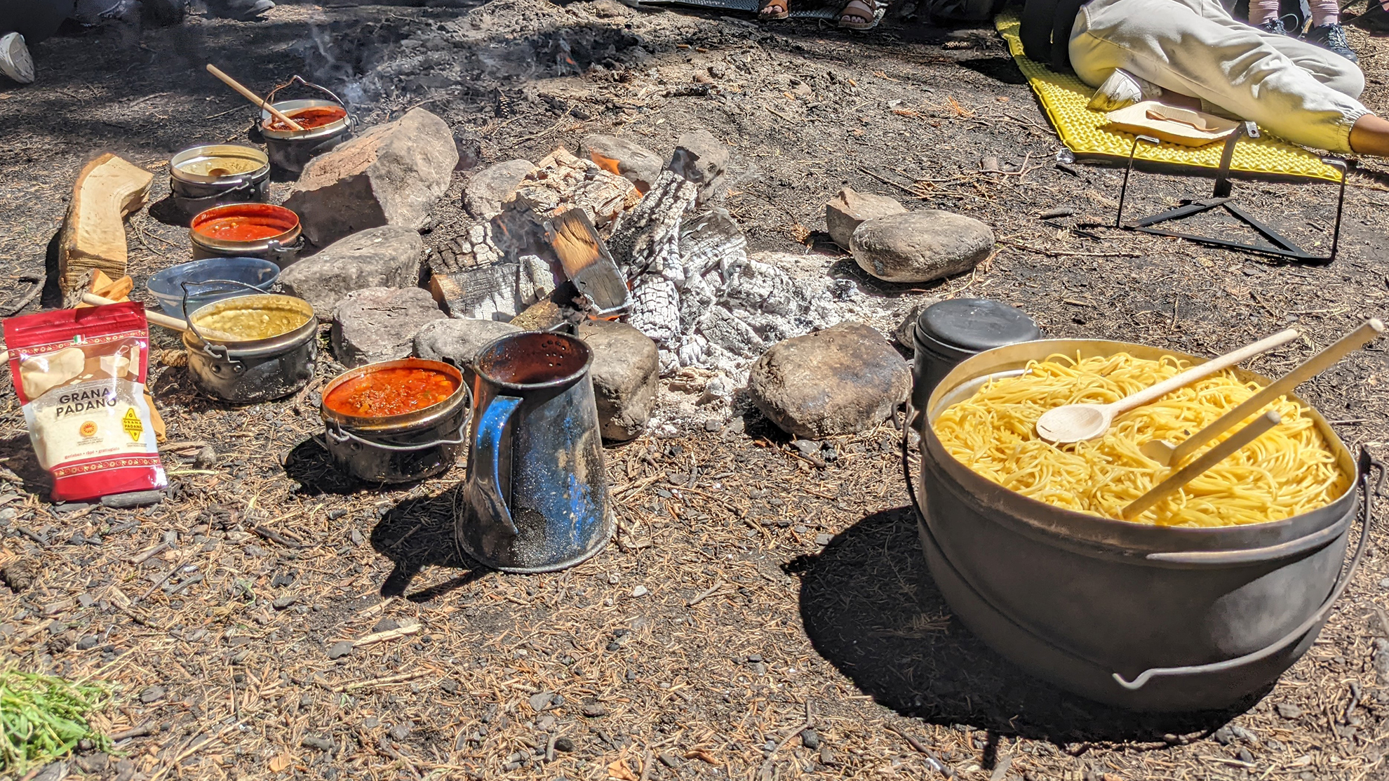 Feuerstelle mit verschiedenen Saucen und einem grossen Topf Spaghetti