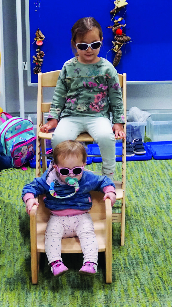 Zwei sehbehinderte Geschwister auf ihren Stühlen mit Sonnenbrillen