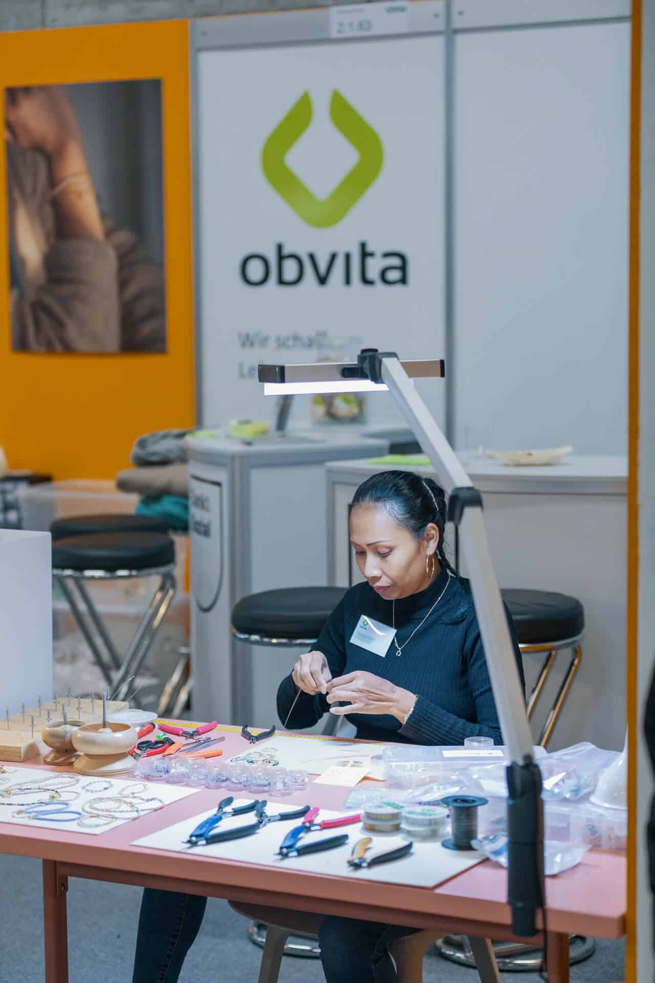 Eine Person fertigt ein Armband in der obvita Schmuckproduktion an.
