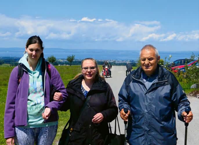 Drei Personen machen einen Spaziergang während eines Ausflugs der obvita Talentwerkstatt. Sie sind auf einem Wanderweg unterwegs, begleitet von einer weiten Aussicht auf die Landschaft.